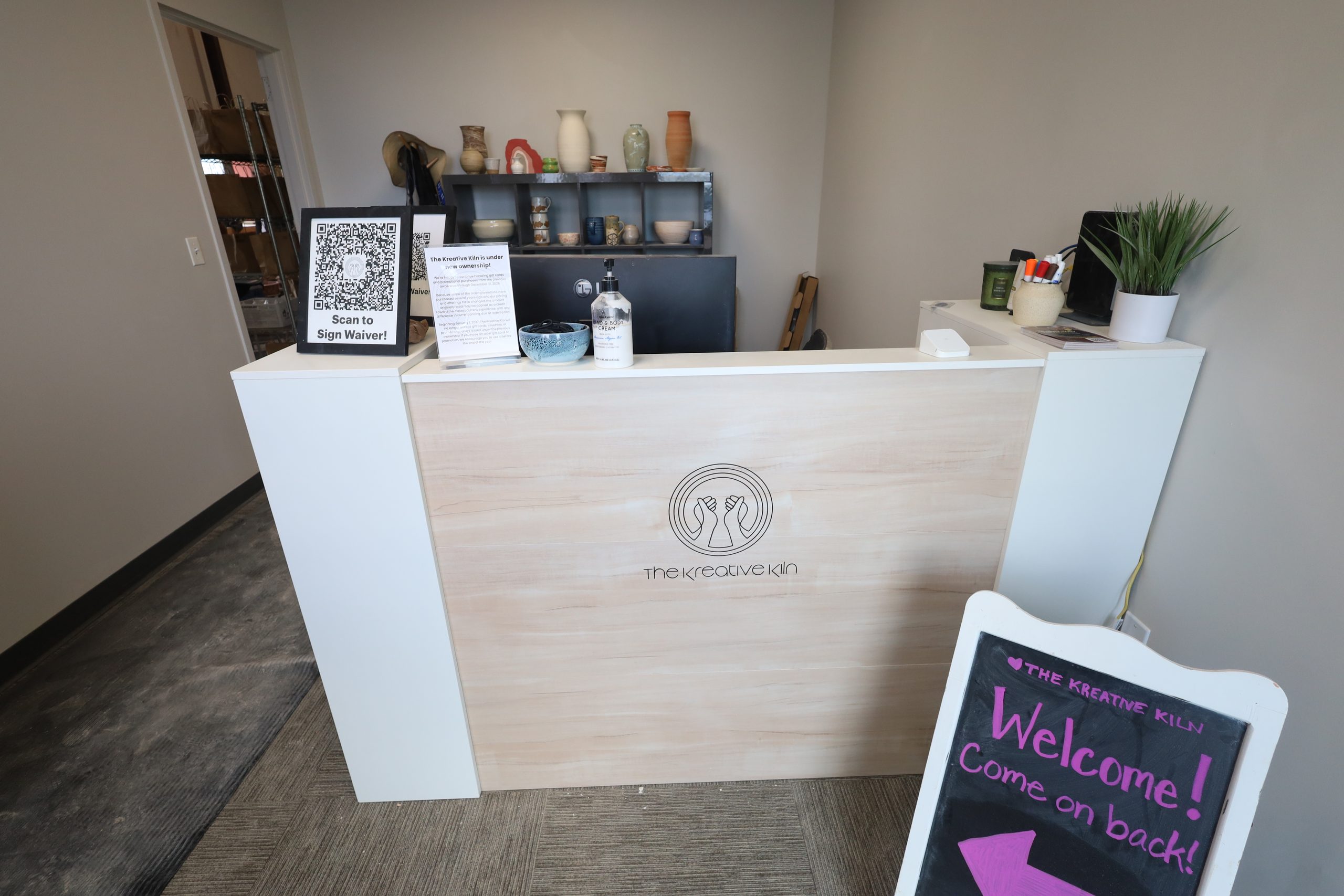 The front desk, with a welcome sign pointing visitors into the studio