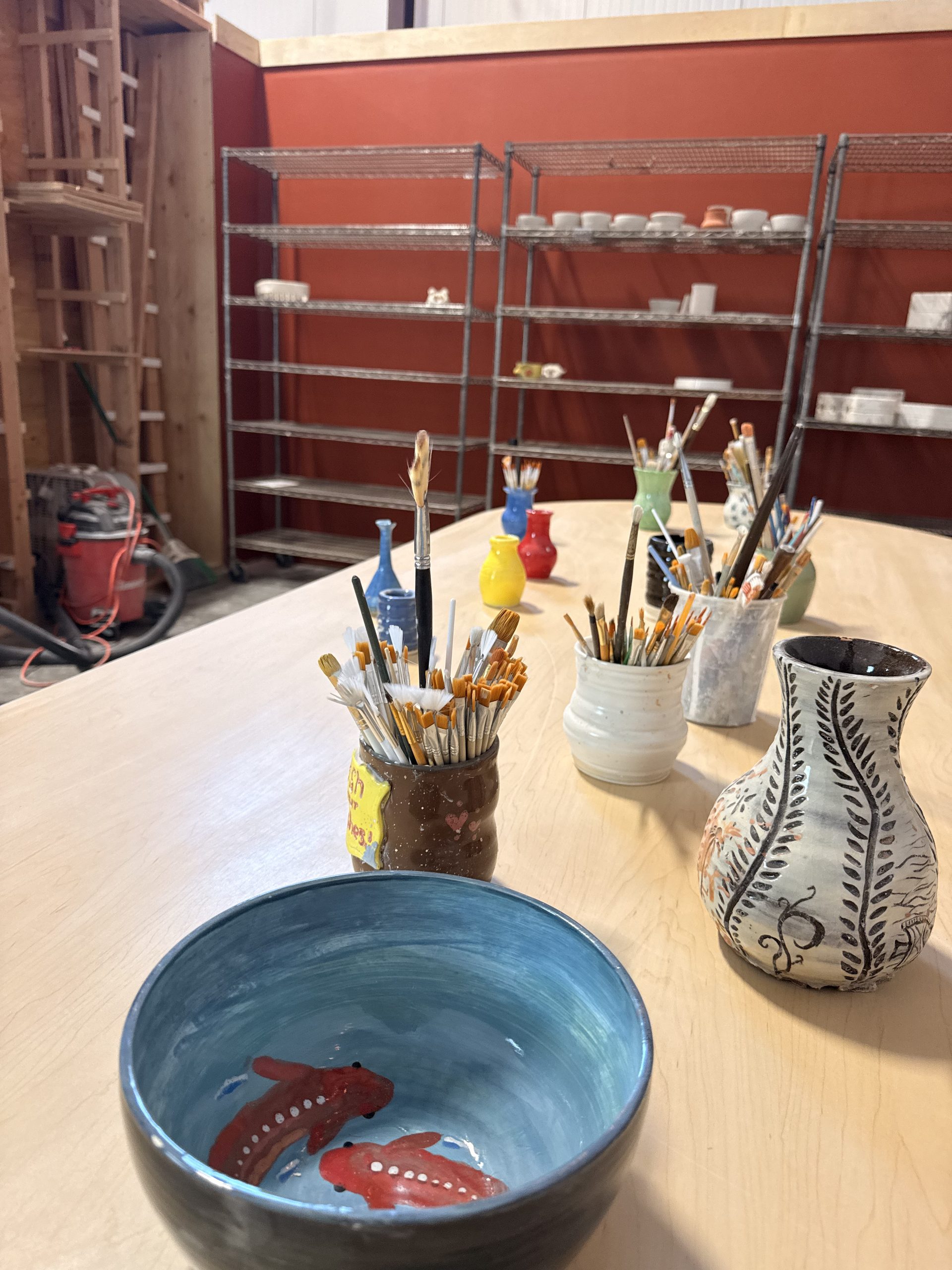 A hand-painted koi bowl and carved vase on the project table